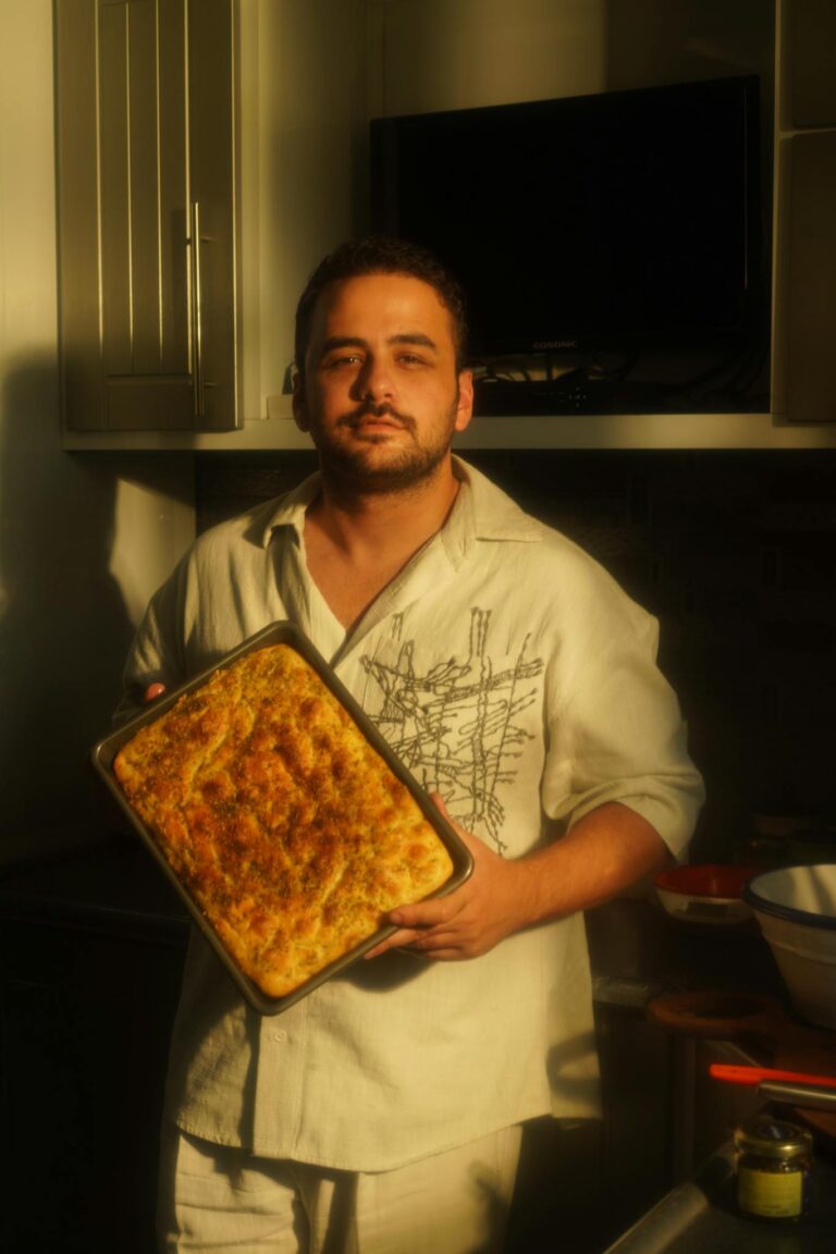 A man proudly displays a freshly baked dish in a warmly lit kitchen. Perfect for showcasing culinary skills.