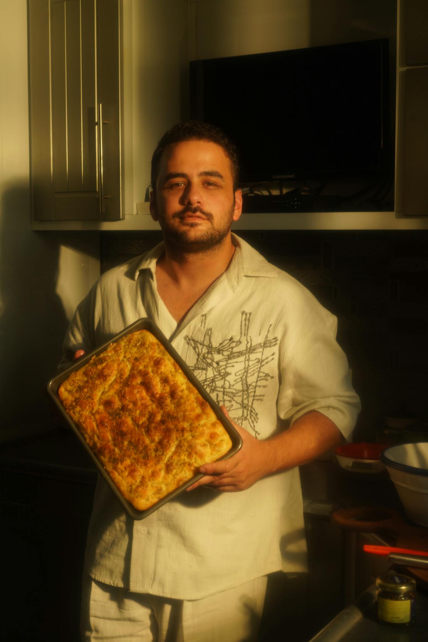 A man proudly displays a freshly baked dish in a warmly lit kitchen. Perfect for showcasing culinary skills.