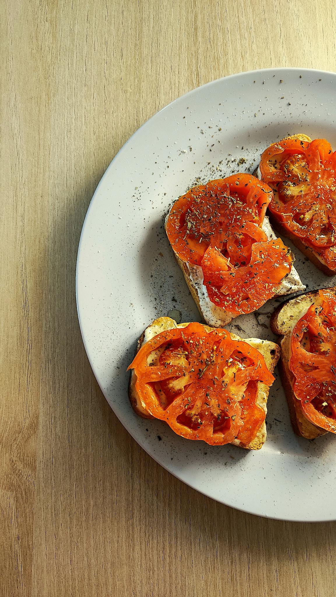 Appetizing tomato bruschetta with herbs served on a white plate, showcasing simple food aesthetics.